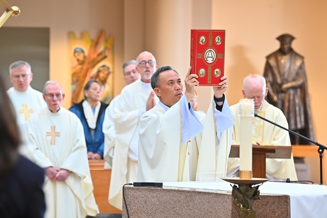 Priest holding up book in St. Thomas More Church