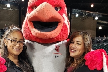Johnny Thunderbird posing with two females in baseball stands