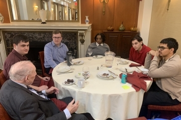 Students at a table with alumnus John Clarke