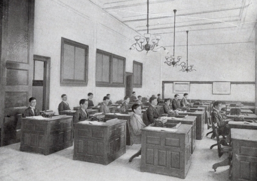 Students sitting at desks in the 1900s using typewriters