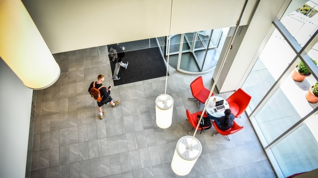 Student sitting at chairs and student walking through lobby of building