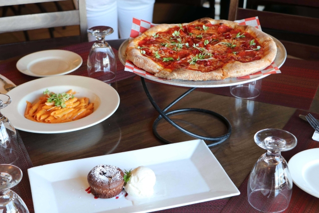 Table at a restaurant with pizza, pasta and dessert 