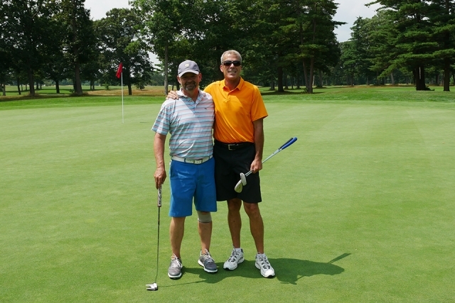 Two St. John's alumni and friends posing for a picture on the golf course