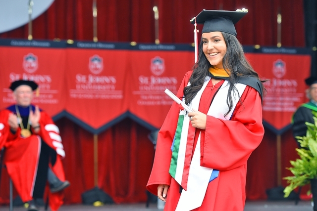 A graduate poses for a photo onstage