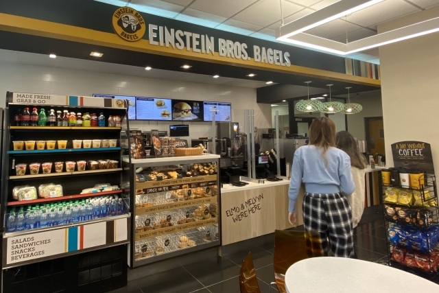 Einstein Bros Bagels featuring two students reviewing the menu while waiting to order
