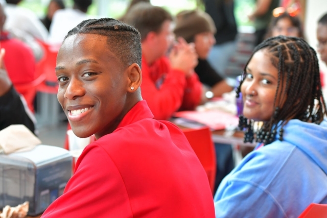 Students at a table smile for a photo