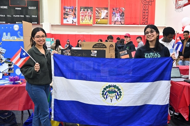 Two female organization members pose with a flag