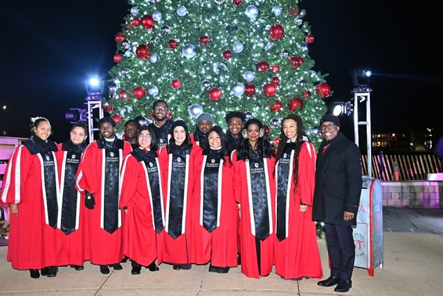 St. John's University Choir posing infront of the Christmas tree 