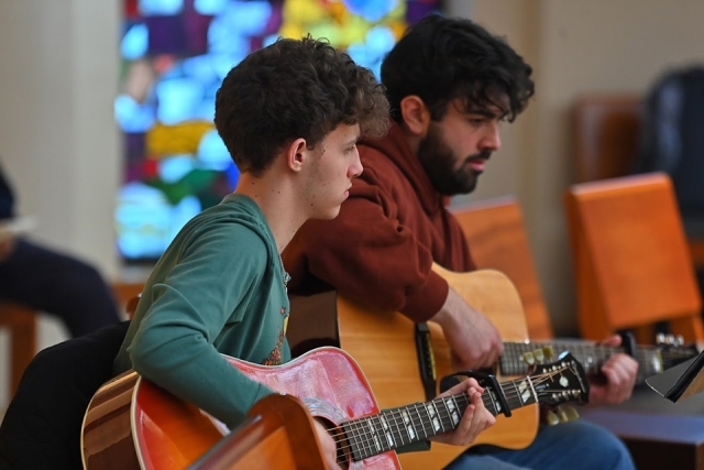 Two men playing guitar inside church