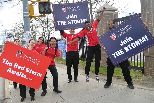St. John's Ambassadors holding signs at the gate welcoming accepted students