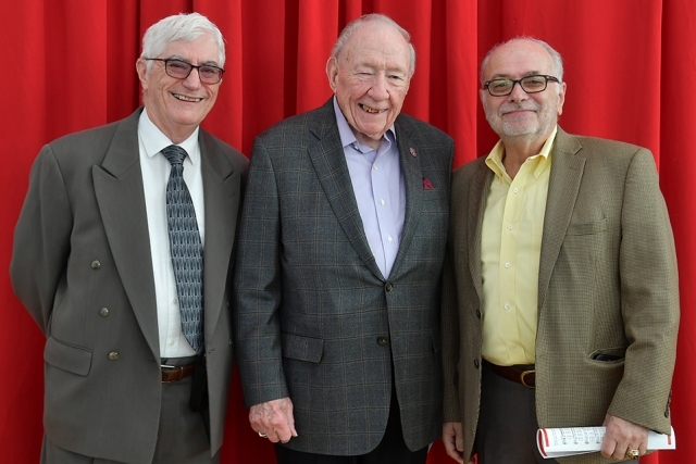 Three St. John's Staten Island campus community members pose for a photo in front of a red curtain