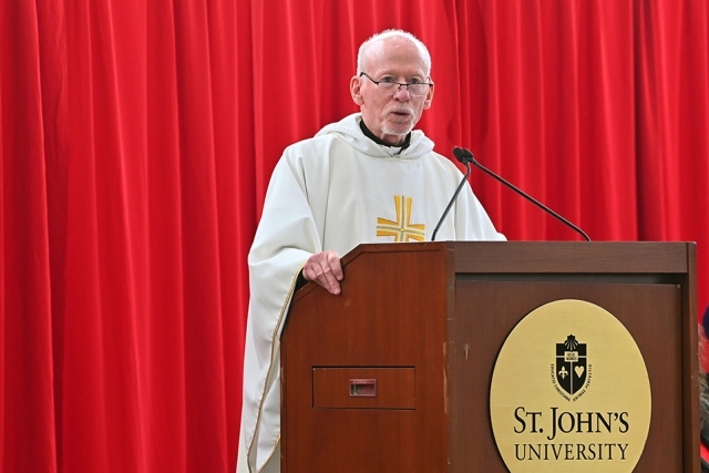 Fr. Shanley speaking at podium in front of red curtains