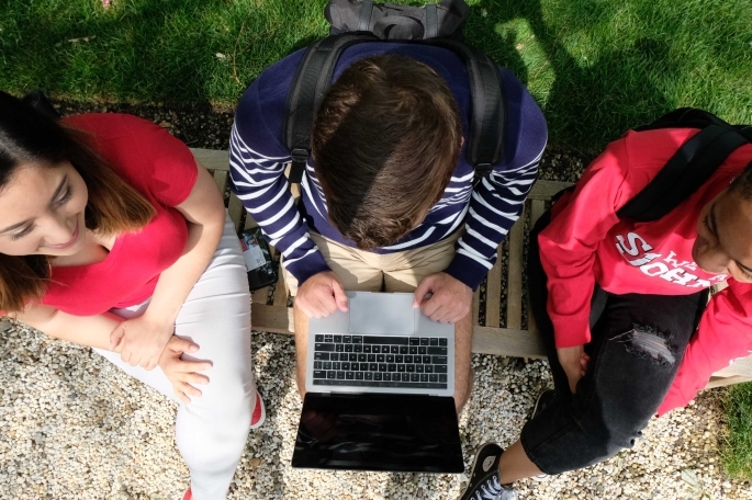 Overhead shot of three students looking at laptop