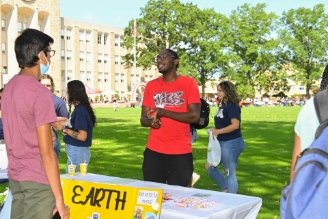 Student behind table with sign that reads Earth Club