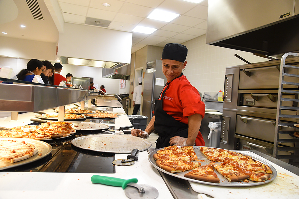 Dining hall worker making pizza