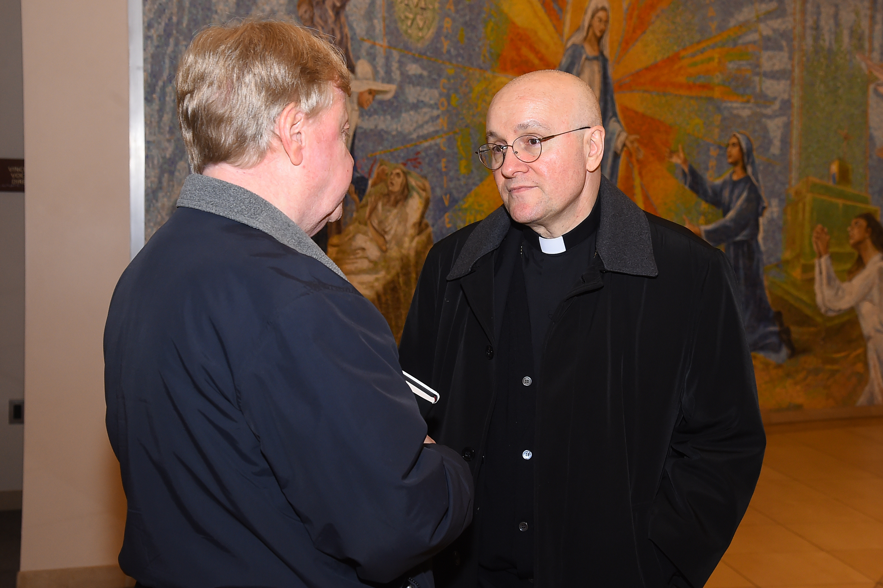 Priest talking to lecture attendee