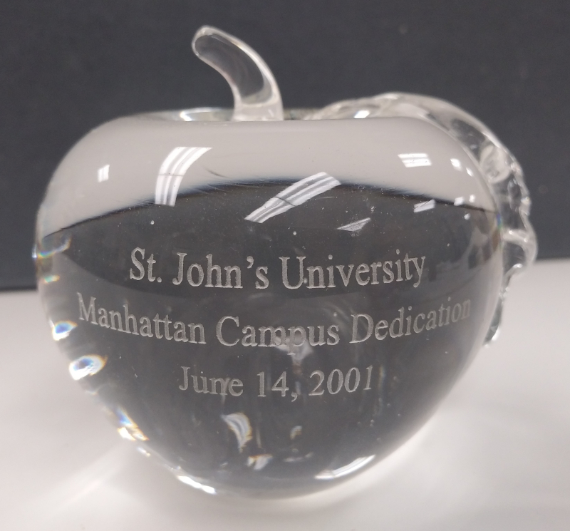 Clear glass apple shaped paper weight engraved with St. John's University Manhattan Campus Dedication Ceremony, June 14, 2001.