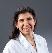 Professional head shot of Professor Sandra E. Reznik wearing a white top.  Image has a gray background.