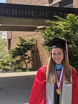 Marisa Murgolo in her cap and gown in front of The School of Education building