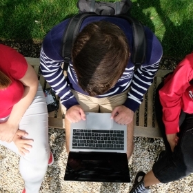 Overhead shot of three students looking at laptop