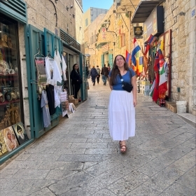 Girl in blue shirt and white long shirt standing in the middle of a street in Italy 