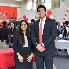 Two students in professional attire for a career fair event 