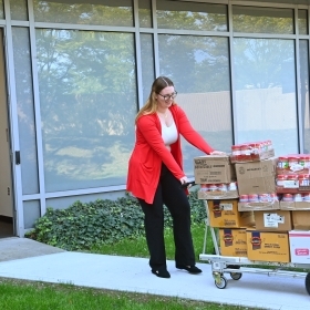 Student pulling food into a food pantry 