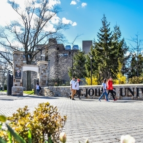 St. John's University front gate with students walking on/off campus