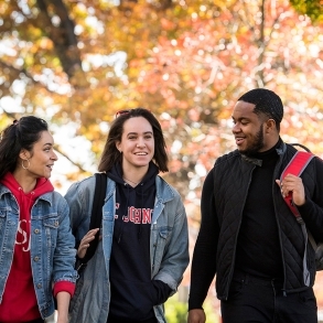 Three students walking outside during a fall day