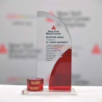 Close-up of the New York Blood Center Milestone Award presented to St. John’s University, displayed against a branded backdrop.