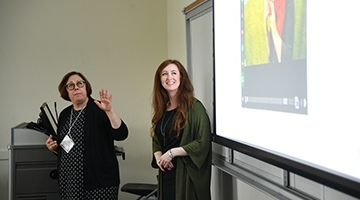 Female Professor teaching in front of screen 