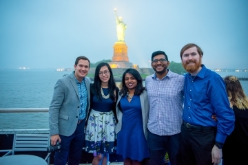 St. John's Alumni pose on a boat with the statue of liberty behind them.