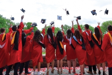 Students throwing commencement caps in air