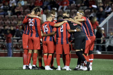 St. John's Men's Soccer team in a huddle on a soccer field