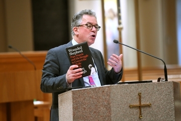 Austen Ivereigh holding up book and speaking into microphone