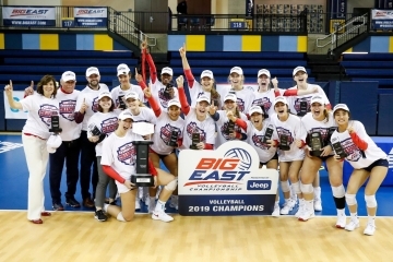 Women's volleyball team poses with big east championship sign