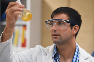 Anthony Tedaldi holding a test tube and wearing chemical goggles