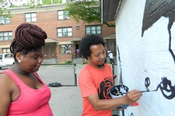 Iandry Randriamandroso painting on a wall