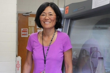 Rachel Zufferey, Ph.D. standing in the lab wearing a purple shirt