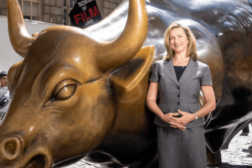 Woman standing in front of bull statue