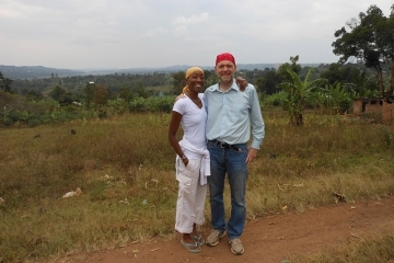 Man and woman pose for a picture outside in Uganda in a field