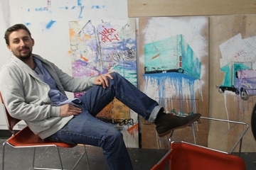 Henry Cunningham ’15C sitting in front of his canvasses