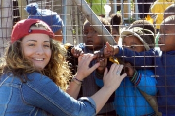 Kerry Andreozzi at a fence with small children on the other side
