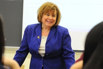 Nina Dorata, Ph.D., CPA, ‘79CBA, ‘88MBA in front of class smiling