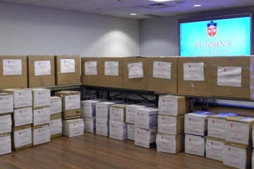 Boxes with labels infront of TV with St. John's Logo