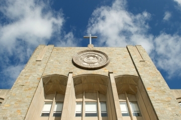 Top of St. Augustine Building featuring cross and St. John's University Seal