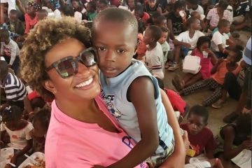 Female holding child while smiling at camera