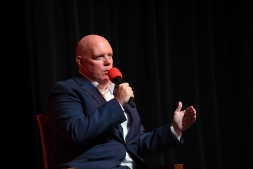 Kevin M. Ryan speaking on stage at event holding microphone