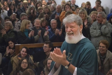 Fr. Pedro Opeka clapping his hands with a crowd behind him