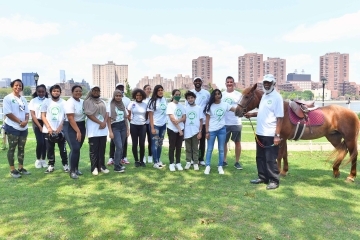 George E. Blair, ’67Ed.D. standing with students and a horse